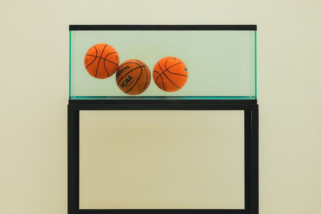 Drei Basketbälle schweben in einem wassergefüllten Glaskasten als Museumsexponat.